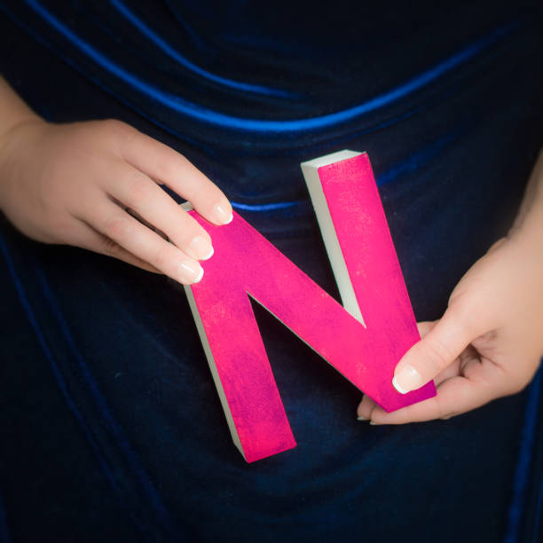istock Pink painted cardboard letter N in manicured hands 852114454