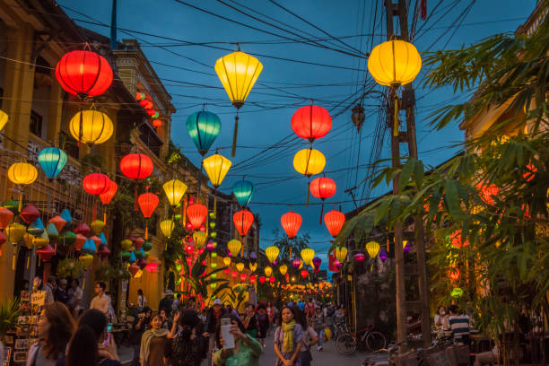 In the streets of Hoi Ans ancient town, in the evening. HOI AN, VIETNAM - January 13, 2017: HOI AN, VIETNAM - January 13, 2017: Bright Lanterns hanging over the walking street, in the ancient of Hoi An. The ancient town, is a popular tourist area. The streets are usually filled with tourists day and night. It's also classed as UNESCO world heritage site. hoi an stock pictures, royalty-free photos & images