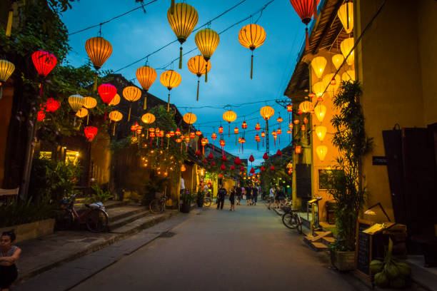 In the streets of Hoi Ans ancient town, in the evening. HOI AN, VIETNAM - January 13, 2017: Bright Lanterns hanging over the walking street, in the ancient of Hoi An. The ancient town, is a popular tourist area. The streets are usually filled with tourists day and night. It's also classed as UNESCO world heritage site. hoi an stock pictures, royalty-free photos & images