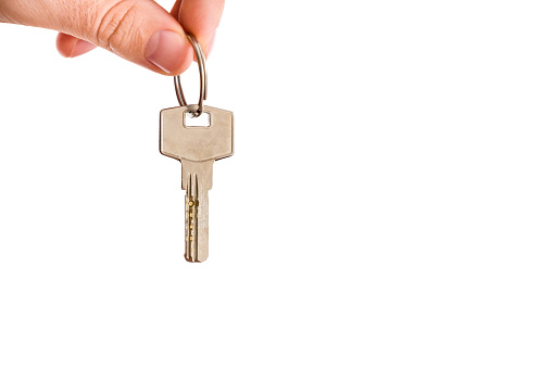 Man's hand giving a new metal key of house isolated on the white background.