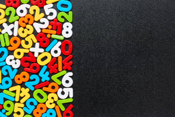 Overhead view of multi colored numbers and symbols on blackboard Overhead view of multi colored numbers and mathematical symbols arranged on blackboard. Flat lay of plastic digits on black slate. Empty space can be used for advertisement. number magnet stock pictures, royalty-free photos & images