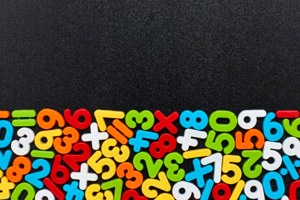 Overhead view of colorful mathematical symbols on blackboard Overhead view of colorful numbers and mathematical symbols on black slate. Flat lay of multi colored digits on blackboard. Blank space can be used for advertisement. number magnet stock pictures, royalty-free photos & images