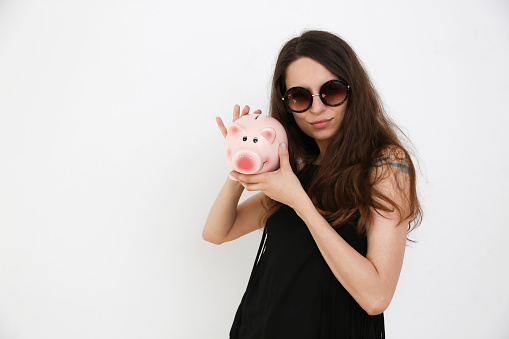 Pig piggy bank and coins, A beautiful girl is holding a piggy bank in her hands,