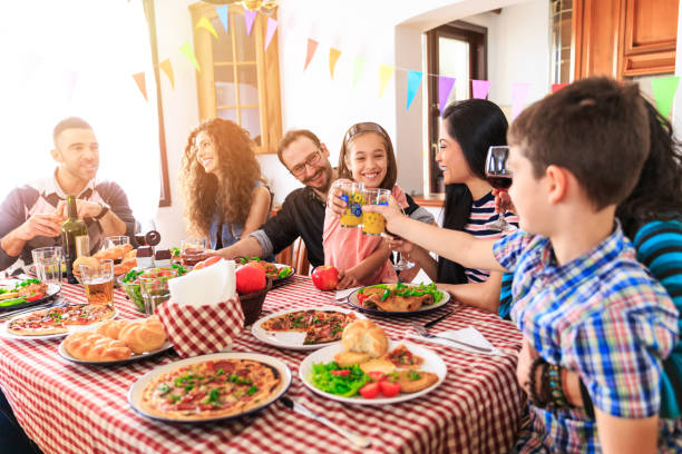 familia la cena en casa - los niños y los padres brindis bebidas mientras almuerza fotografías e imágenes de stock