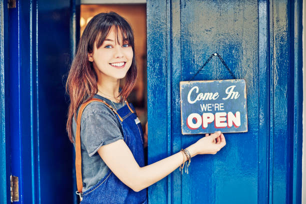 istock Female owner hanging open sign on deli front door 852152178