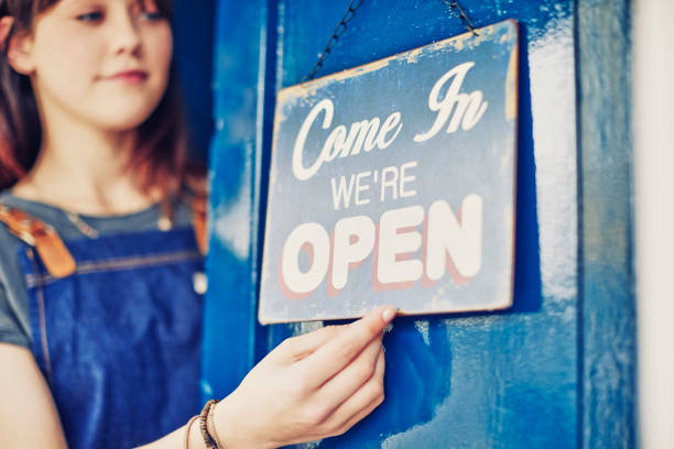 istock Female entrepreneur hanging open sign on deli front door 852156572