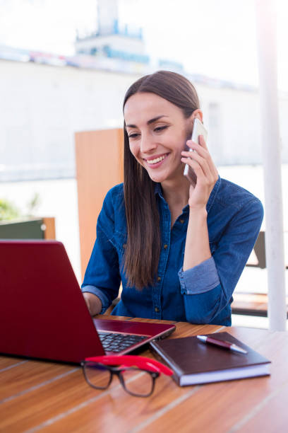 istock I will be waiting for your call. Beautiful smiling woman talking on the phone while working on a laptop outdoors 852162342