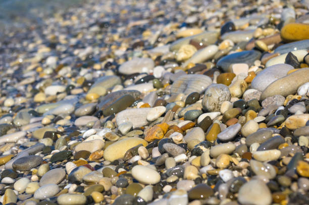 istock sea pebble beach with multicoloured stones, waves with foam 852185272