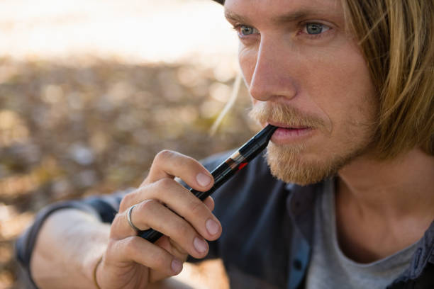 istock Man smoking an electronic cigarette in the park 852187844