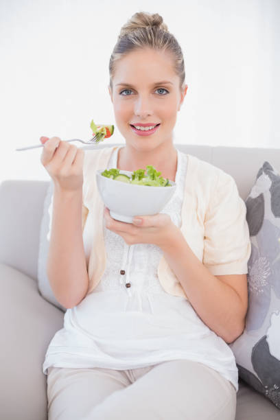 istock Happy fresh model holding healthy salad sitting on sofa 852188500