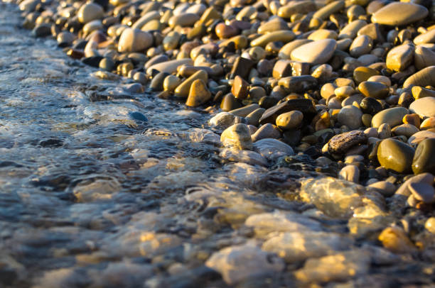 istock sea pebble beach with multicoloured stones, waves with foam 852192422