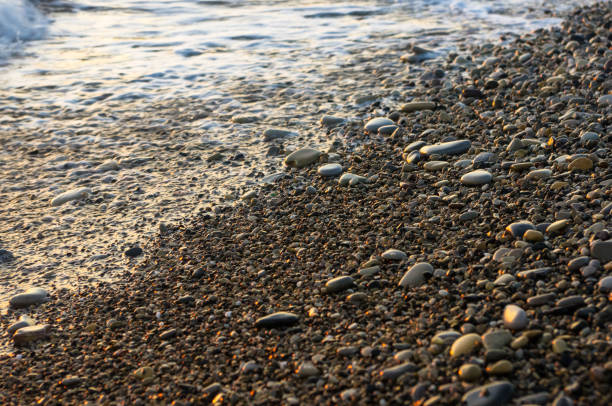 istock sea pebble beach with multicoloured stones, waves with foam 852195698