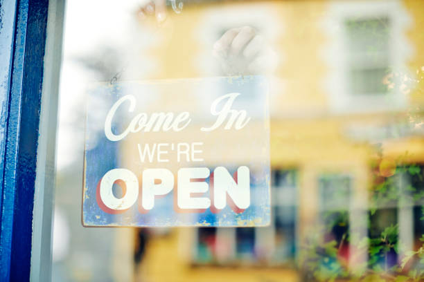 istock Female deli owner hanging open sign seen through window 852195952