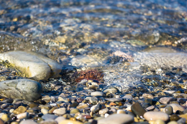 istock sea pebble beach with multicoloured stones, waves with foam 852196040