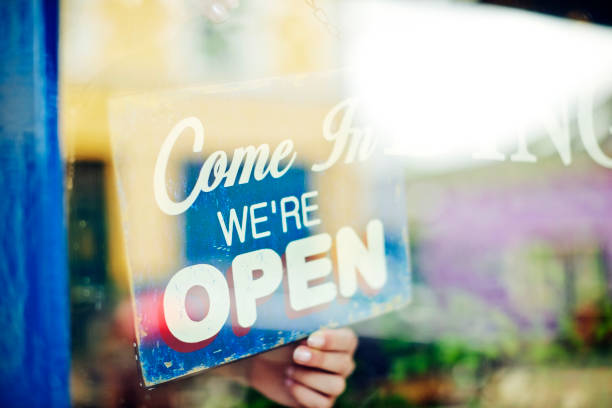 istock Deli owner hanging open sign seen through store window 852196250