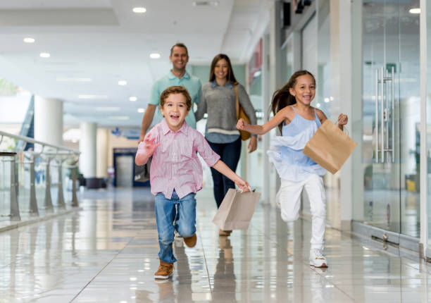 familia de compras y corriendo hacia la cámara en el centro comercial - spending money fotos fotografías e imágenes de stock