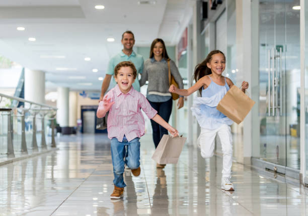 Family shopping and running towards the camera at the mall Happy Latin American family shopping and running towards the camera at the mall - lifestyle concepts shopping mall stock pictures, royalty-free photos & images