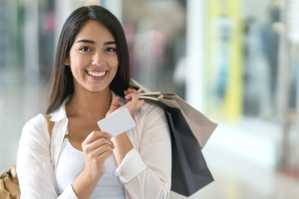 Woman shopping with a credit card at the mall Portrait of a happy woman shopping with a credit card at the mall and looking at the camera smiling reduction looking at camera finance business stock pictures, royalty-free photos & images