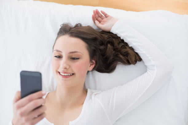 istock Young brunette looking at mobile phone in bed 852217804