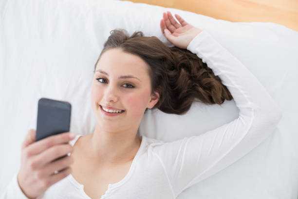 istock Young brunette with mobile phone in bed 852217816