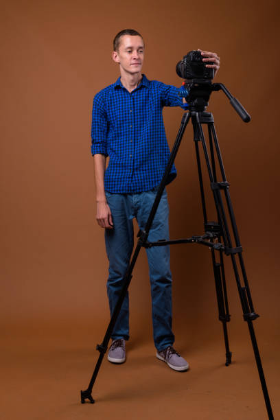 istock Studio shot of young man getting ready for vlogging while wearing blue checkered shirt against colored background 852228684
