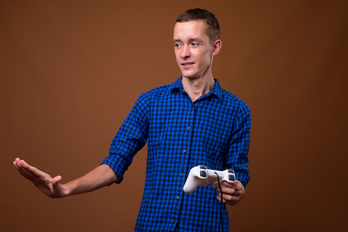 Studio shot of young man playing games against colored background horizontal shot