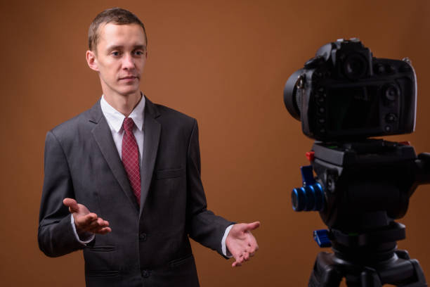 istock Studio shot of young businessman wearing suit while vlogging against colored background 852232520