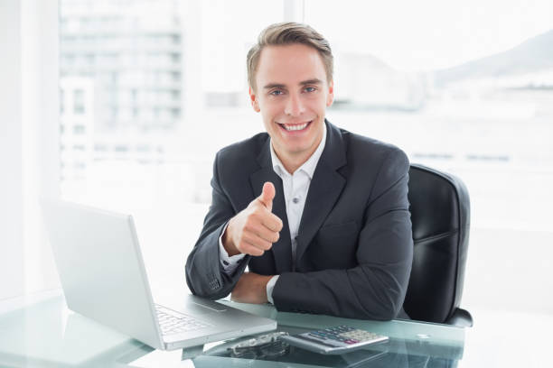istock Businessman with laptop gesturing thumbs up at office desk 852276714