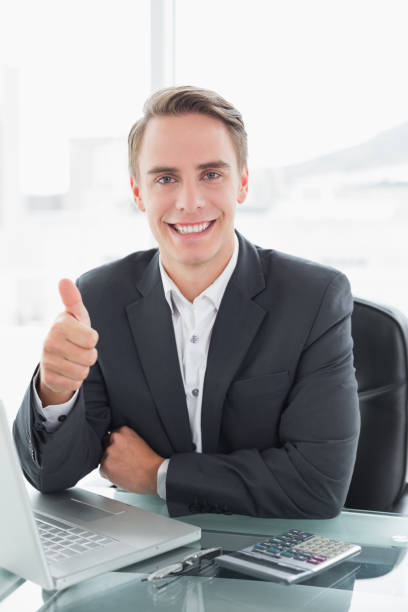 istock Businessman with laptop gesturing thumbs up at office desk 852276728