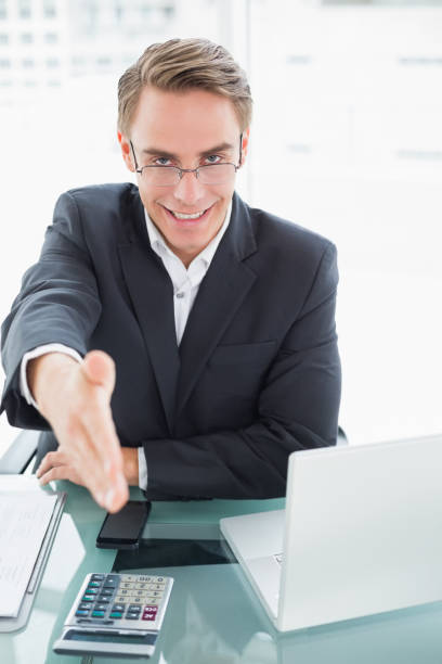 istock Elegant businessman offering a handshake at office desk 852282396