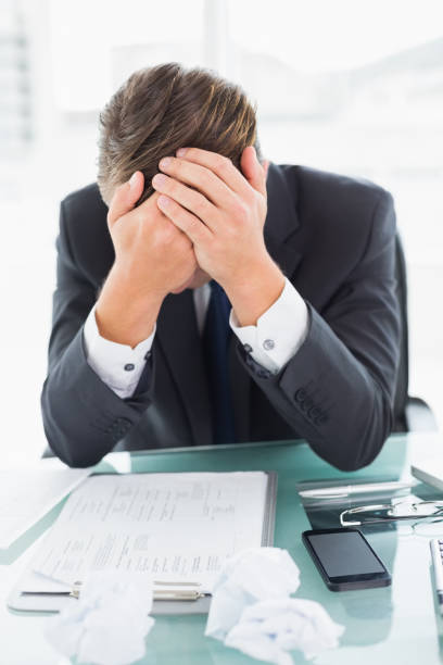 istock Worried businessman with head in hands at office desk 852282434