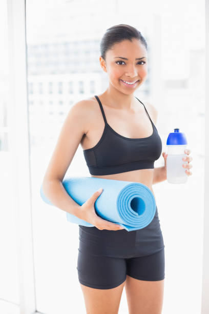 istock Cute dark haired model in sportswear carrying exercise mat and water 852285598