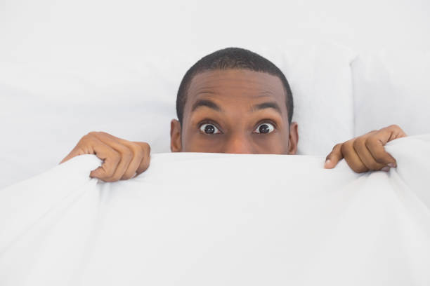 istock Shocked Afro man covering face with sheet in bed 852292742