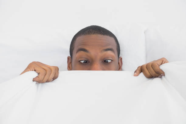 istock Shocked Afro man covering face with sheet in bed 852292748