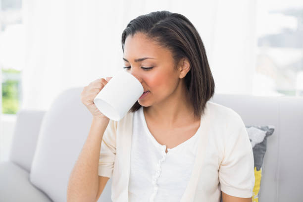 istock Attractive young dark haired woman in white clothes drinking coffee 852293580