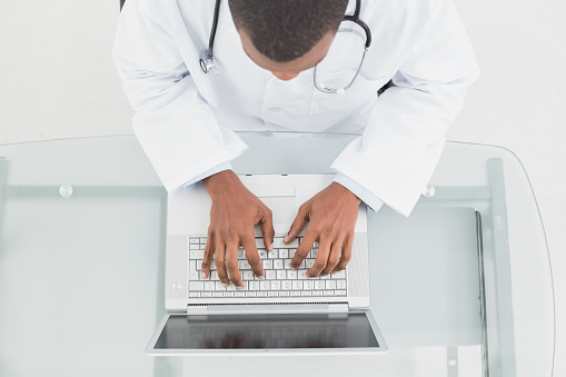 Overhead view of a male doctor using laptop at medical office