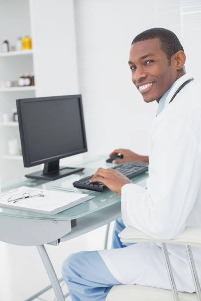 istock Smiling male doctor using computer at medical office 852304004