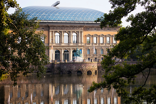 View of a modern art museum (K21, Kunstsammlung Nordrhein-Westfalen) in Dusseldorf through trees. Lake is also in view.