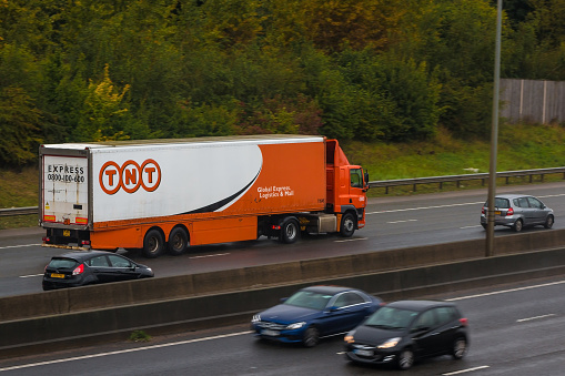 Redbourn: Lorry belonging to TNT Express international courier delivery services company in motion on the British M1 motorway, in a rainy day