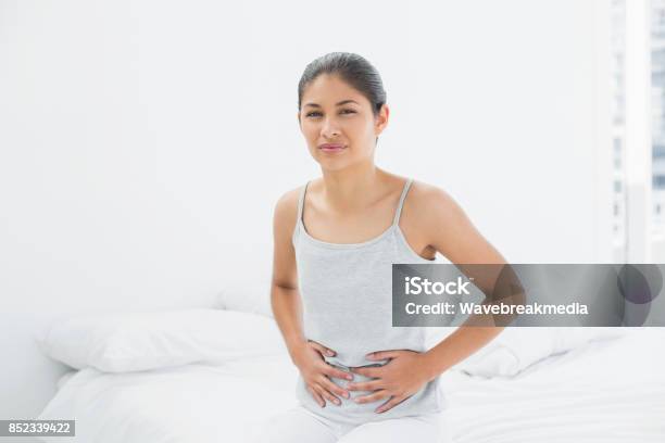 Lässige Frau Mit Magenschmerzen Im Bett Sitzen Stockfoto und mehr Bilder von Hand am Bauch - Hand am Bauch, Eine Frau allein, Frauen