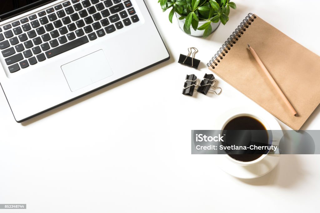 Office workplace with laptop, cup of coffee,sketch-book, accessories on white . Top view with copy space. Office workplace with laptop, cup of coffee,sketch-book, accessories on white background. Top view with copy space. Laptop Stock Photo