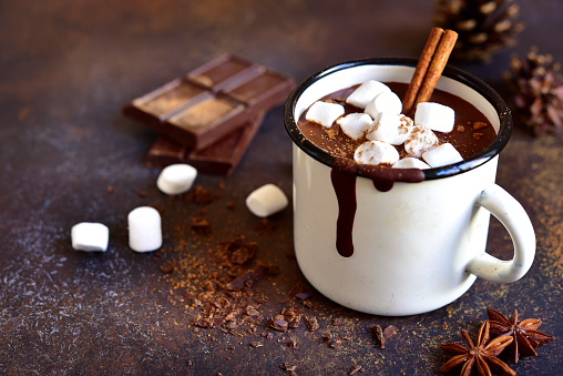 Homemade spicy hot chocolate with cinnamon and marshmallows in enamel mug on a slate,stone or concrete background.