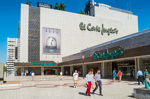 People walk at the El Corte Ingles department store in downtown Malaga, Andalusia, Spain on a sunny day.
