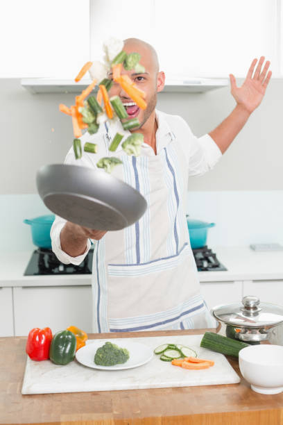 istock Man tossing vegetables in air at kitchen 852400104