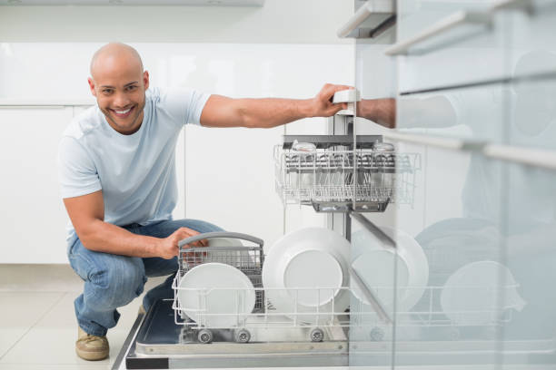 Portrait of a smiling young man using dish washer in the kitchen at home