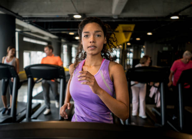 mujer atlética corriendo en el gimnasio - aparatos para hacer ejercicio fotos fotografías e imágenes de stock