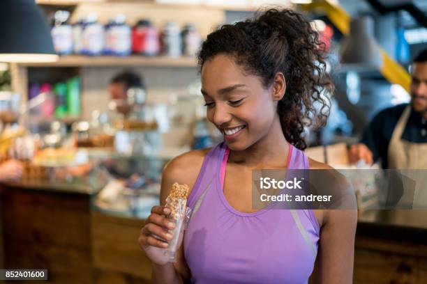 Woman Eating A Protein Bar At The Gym Stock Photo - Download Image Now - Protein Bar, Snack, Eating