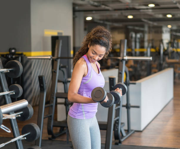 istock Woman training at the gym lifting free weights 852401694