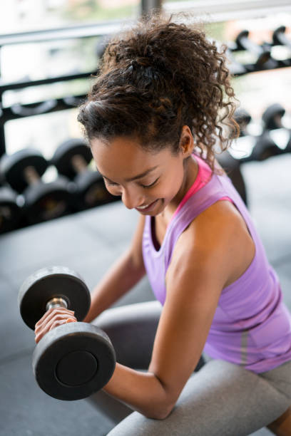 istock Athletic woman exercising at the gym lifting free weights 852401708