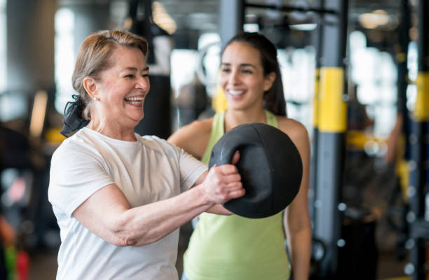femme adulte exerçant dans la salle de sport avec un entraîneur personnel - coach exercising instructor gym photos et images de collection